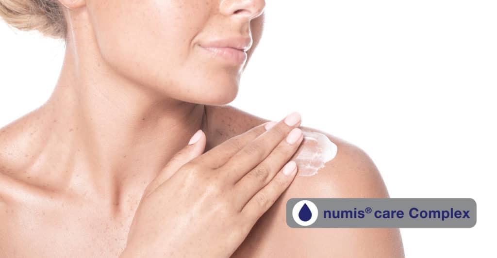 Woman creaming her shoulder with numis® Care Complex