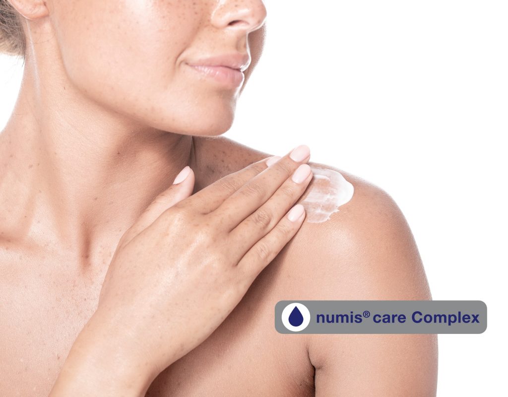 Woman creaming her shoulder and numis® Care Complex